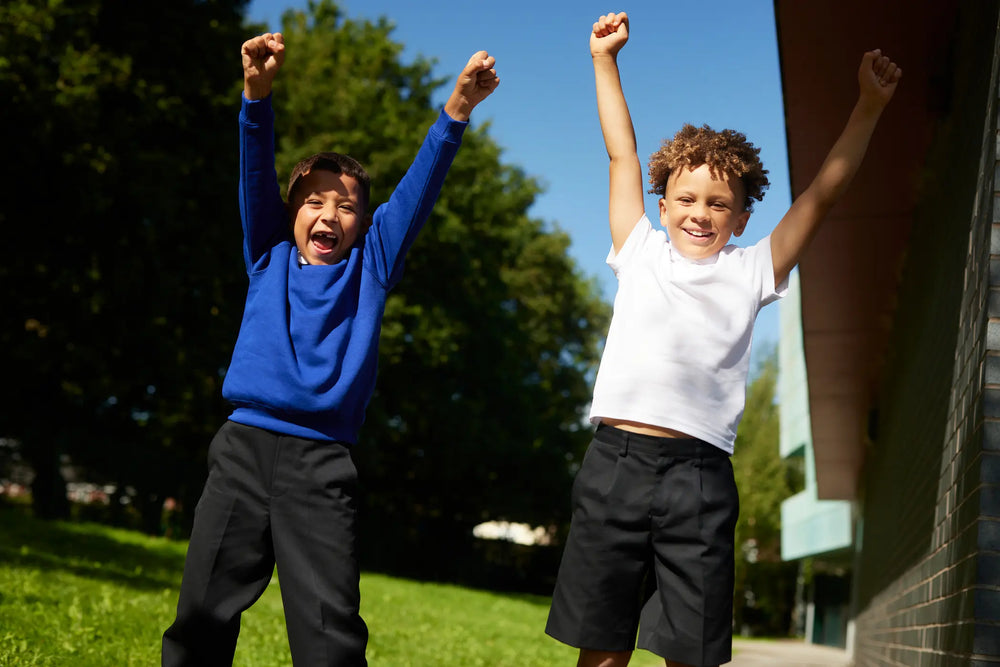 Two school boys jumping with arm in the air